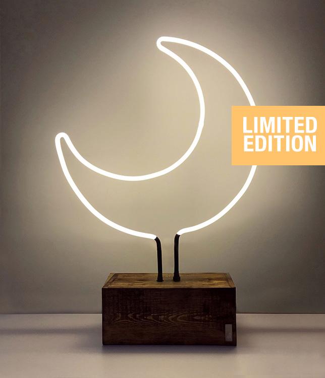 A crescent shape glass neon table light on a wooden base.