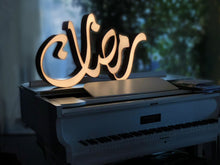 Load image into Gallery viewer, A 1m long ramadan decoration, 3D free standing sign light of the term &quot;Ramadan&quot; in Arabic calligraphy placed on a piano
